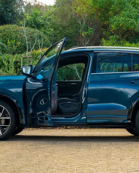 Volkswagen SUV with the driver's door open, parked in a leafy garden