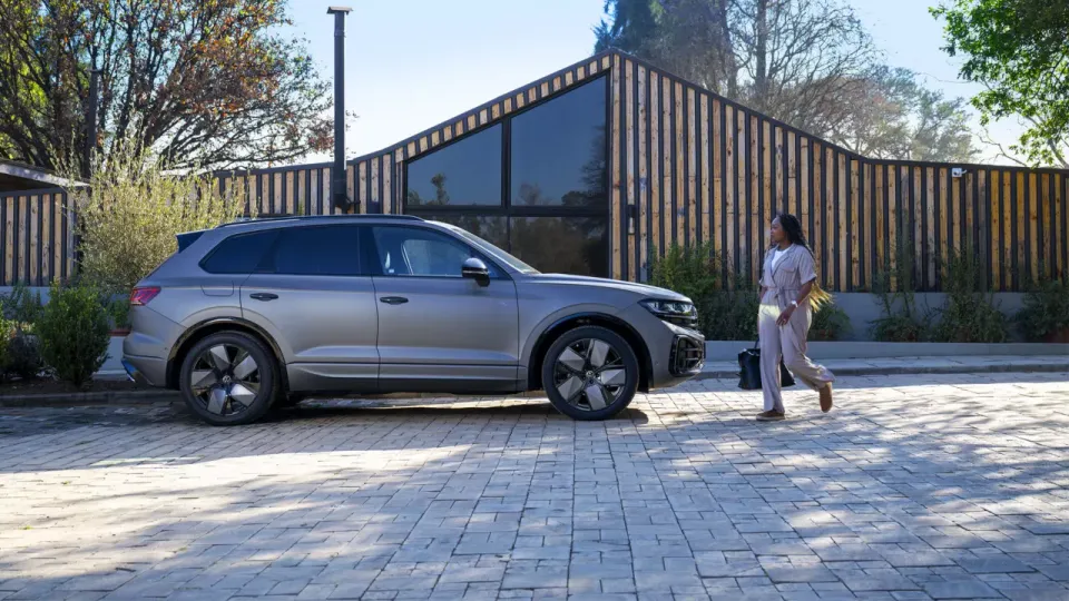 Silver Volkswagen Touareg parked outside a modern wood-clad house